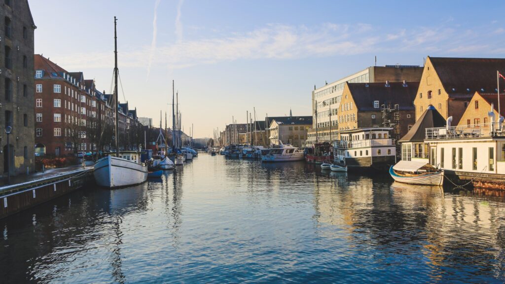 A wide shot of boats on the body of water near buildings in Christianshavn, Copenhagen, Denmark