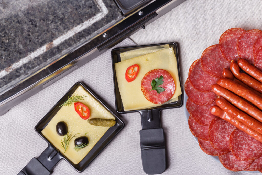 young woman is preparing a traditional Swiss cheese raclette.