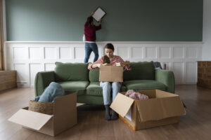 Young couple moving into new home – carrying boxes and smiling during a house relocation
