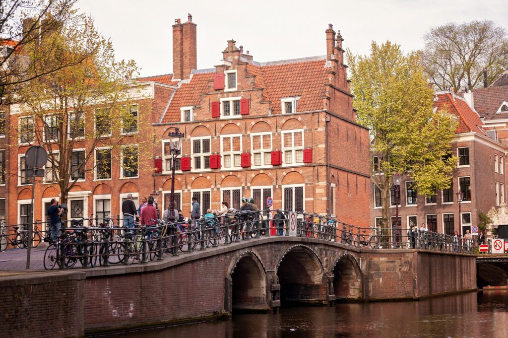 Vintage canal boat passing under an Amsterdam bridge, symbolizing budget relocations by cheap moving companies in the Netherlands