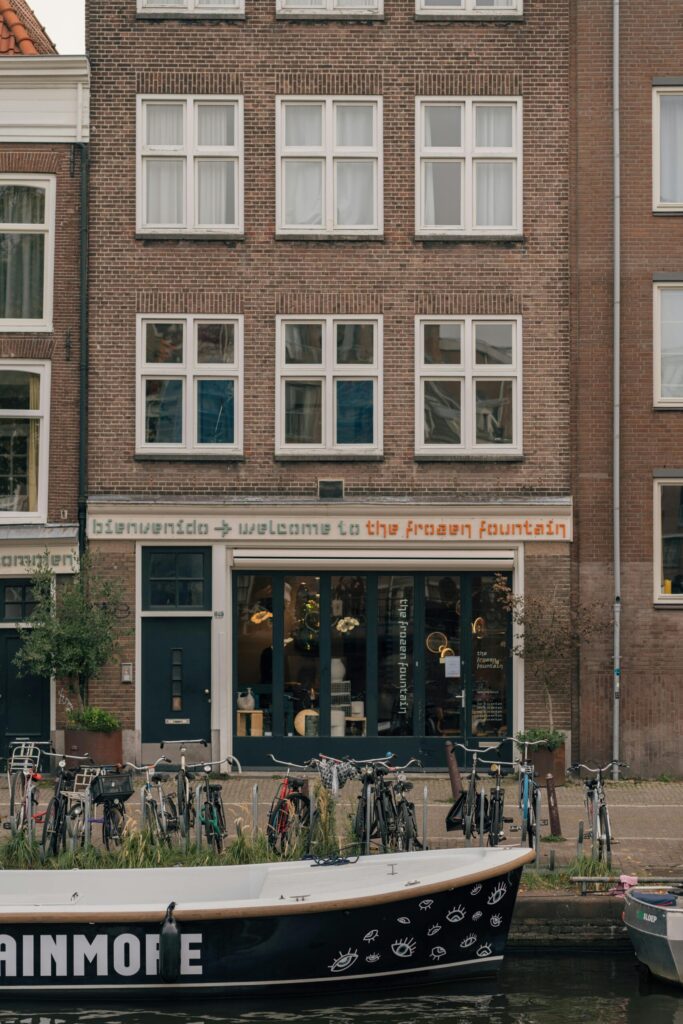 Canal-side brick façade with bikes parked in front of cafés and shops—showcasing everyday Dutch urban charm for expats in the Netherlands.