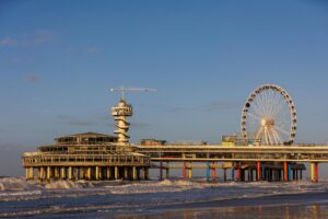 Modern seaside life in the Netherlands – vibrant view of the Scheveningen Pier with Ferris wheel and Bungy tower, representing lifestyle contrast in the context of living in Belgium vs Netherlands.