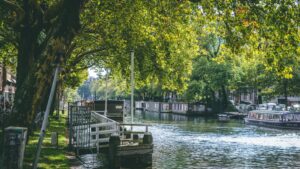 Peaceful canal scene in the Netherlands with trees and houseboats – visualizing the lifestyle contrast in living in France vs Netherlands