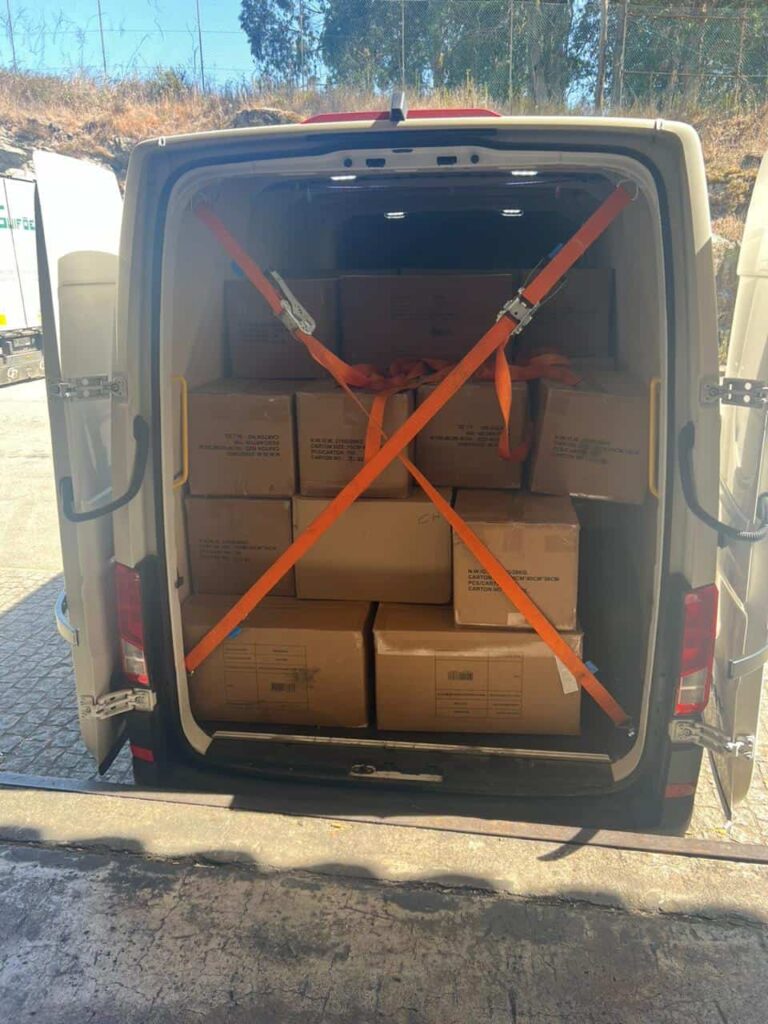 Moving van interior filled with neatly stacked cardboard boxes secured by orange straps, prepared for relocation to Netherlands.