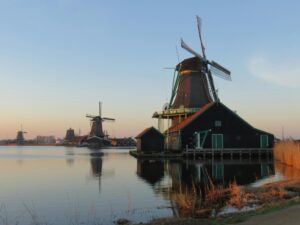 Traditional Dutch windmills by the water at sunset—iconic heritage symbolizing what the Dutch are known for in history and culture.