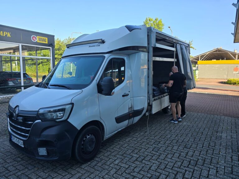 Two 1way movers loading a white Renault moving van from the side in front of a building