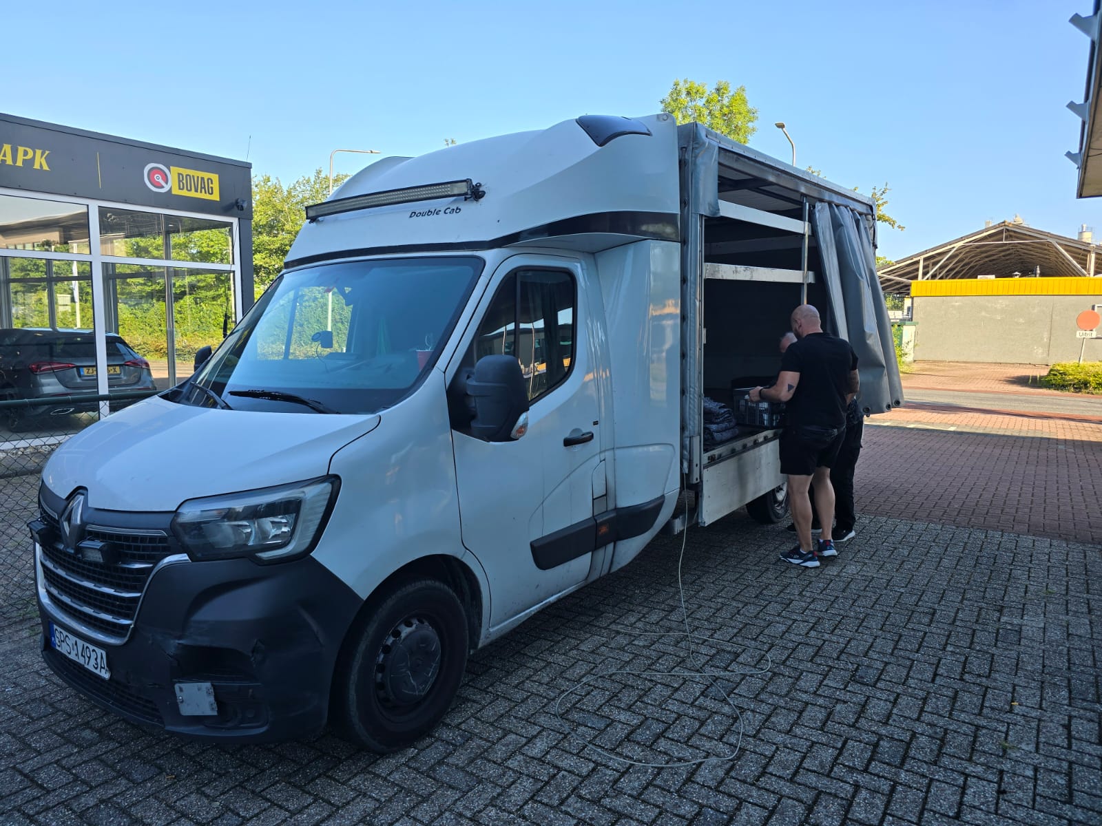 Two 1way movers loading a white Renault moving van from the side in front of a building