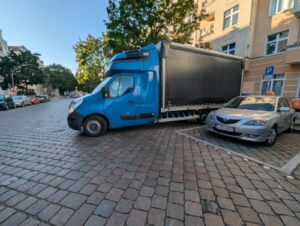 Blue VANonsite style moving truck parked on a cobblestone street in a European city, ready for a household international removal.
