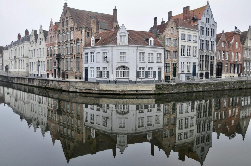 Case storiche a capanna riflettute nel canale in una mattina nebbiosa a Bruges, Belgio