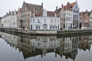 Case storiche a capanna riflettute nel canale in una mattina nebbiosa a Bruges, Belgio
