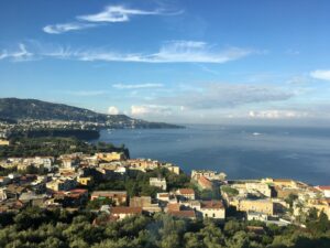 Italian coastal town with colorful houses and boats on a calm blue bay, representing life after moving to Italy with VANonsite European removals